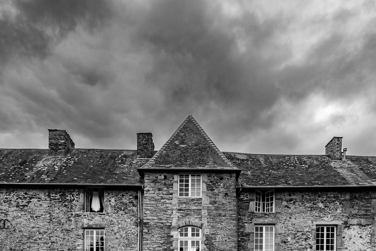 La façade de schiste du Château de la Roque sous un ciel d'orage, en noir et blanc — Théreval (Manche) — Arnaud Chapelle