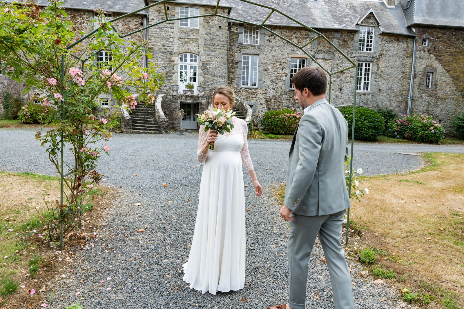 Alexandra et Benjamin devant la façade du château, sous l'arche de roses — Château de la Roque — Arnaud Chapelle