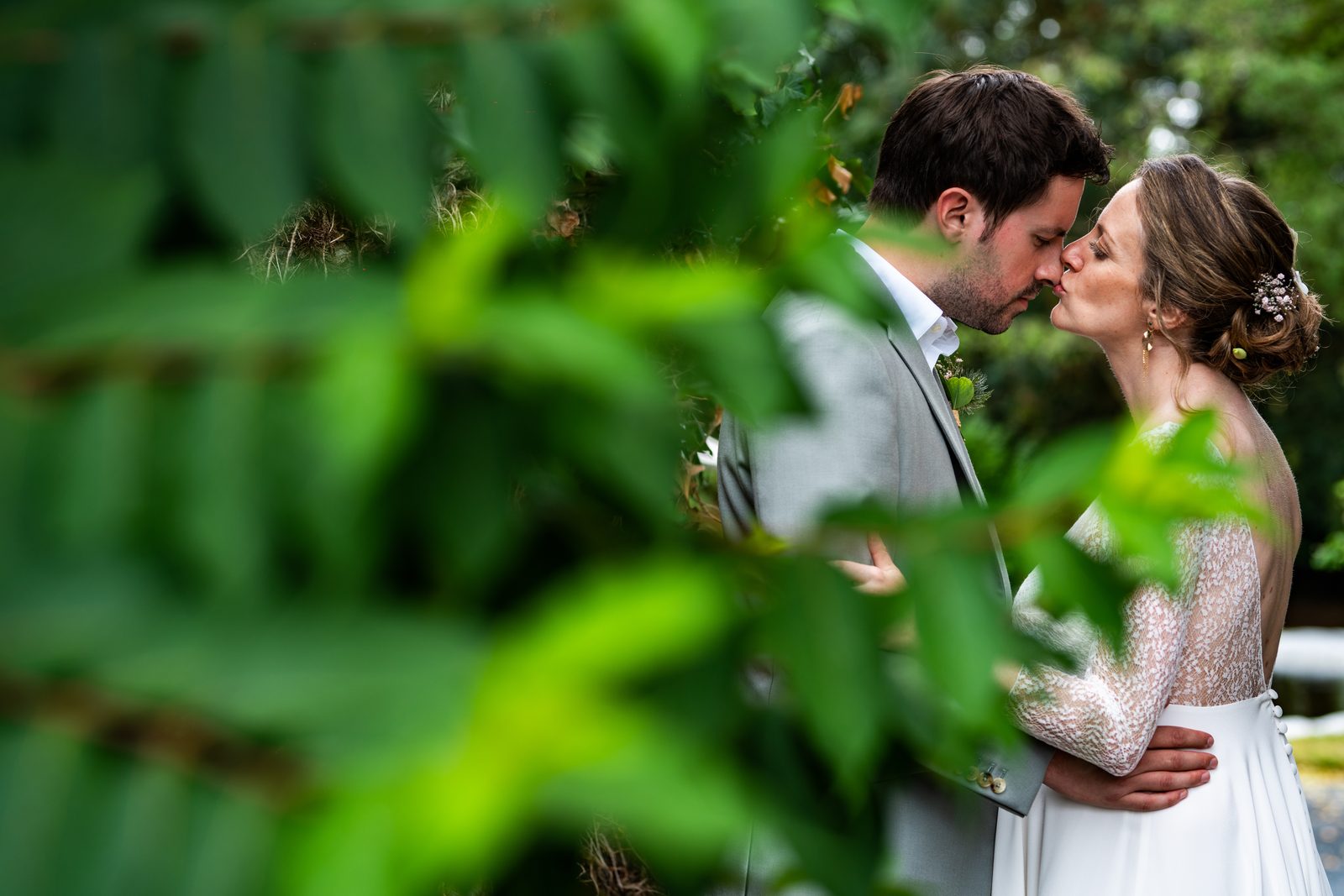 Un baiser à travers le feuillage du parc — mariage au Château de la Roque — Arnaud Chapelle