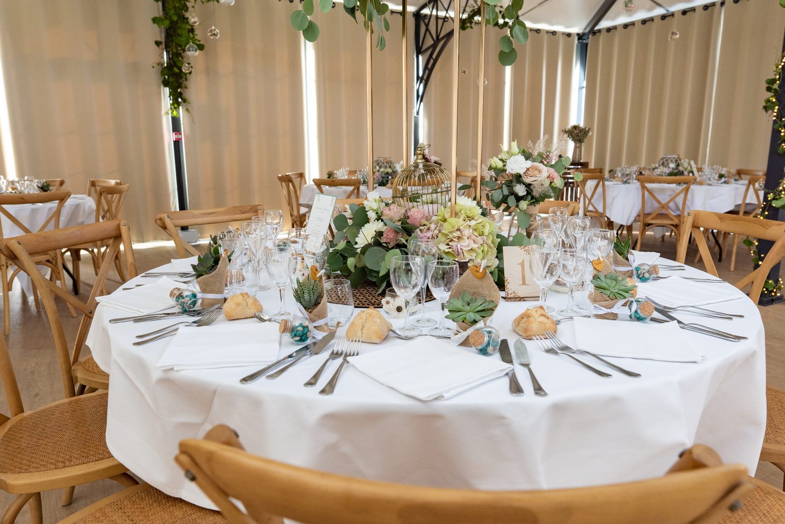 Une table ronde dressée, chaises en bois et fleurs pâles — dîner à L'Orangerie du Château de la Roque — Arnaud Chapelle
