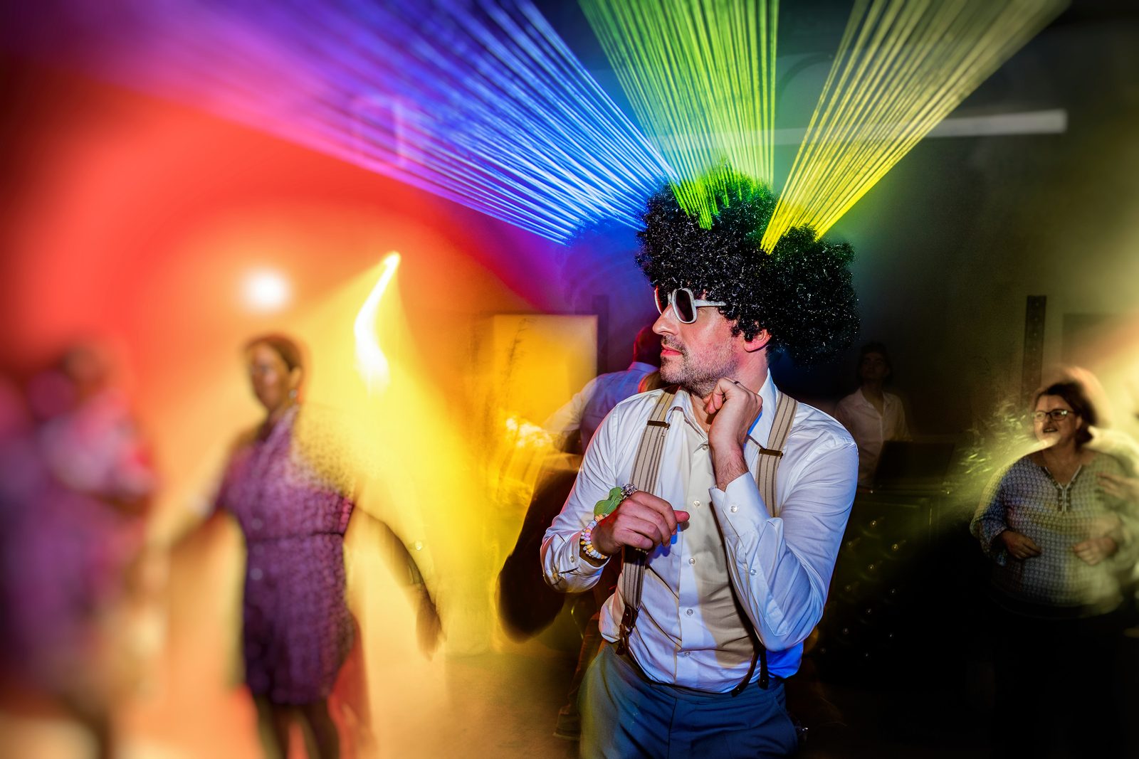 Un invité en perruque sous les lasers — soirée de mariage à L'Orangerie du Château de la Roque — Arnaud Chapelle