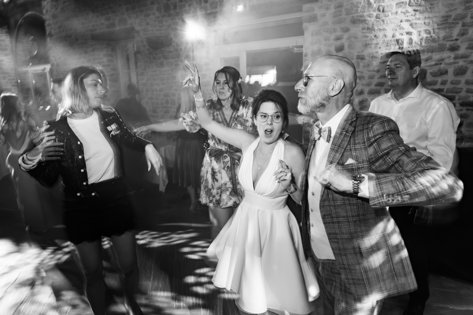 Charlotte et Laurent sur la piste de danse, en noir et blanc, dans la salle de pierre — mariage aux Châteaux de La Lucerne d'Outremer — Arnaud Chapelle