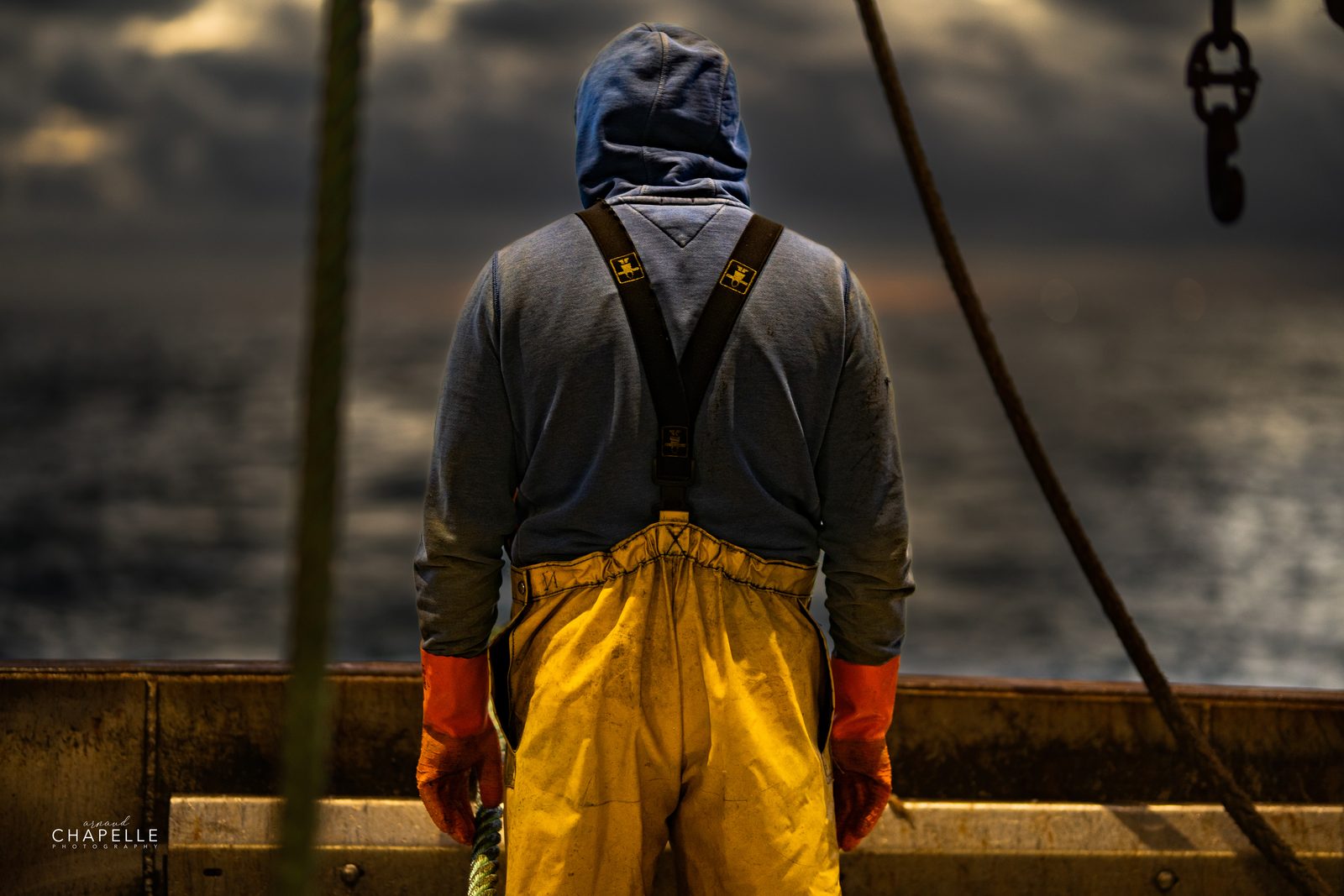 Un marin du Télémaque, de dos, en ciré jaune face à la mer — pêche à la coquille Saint-Jacques au large de Grandcamp-Maisy — Arnaud Chapelle