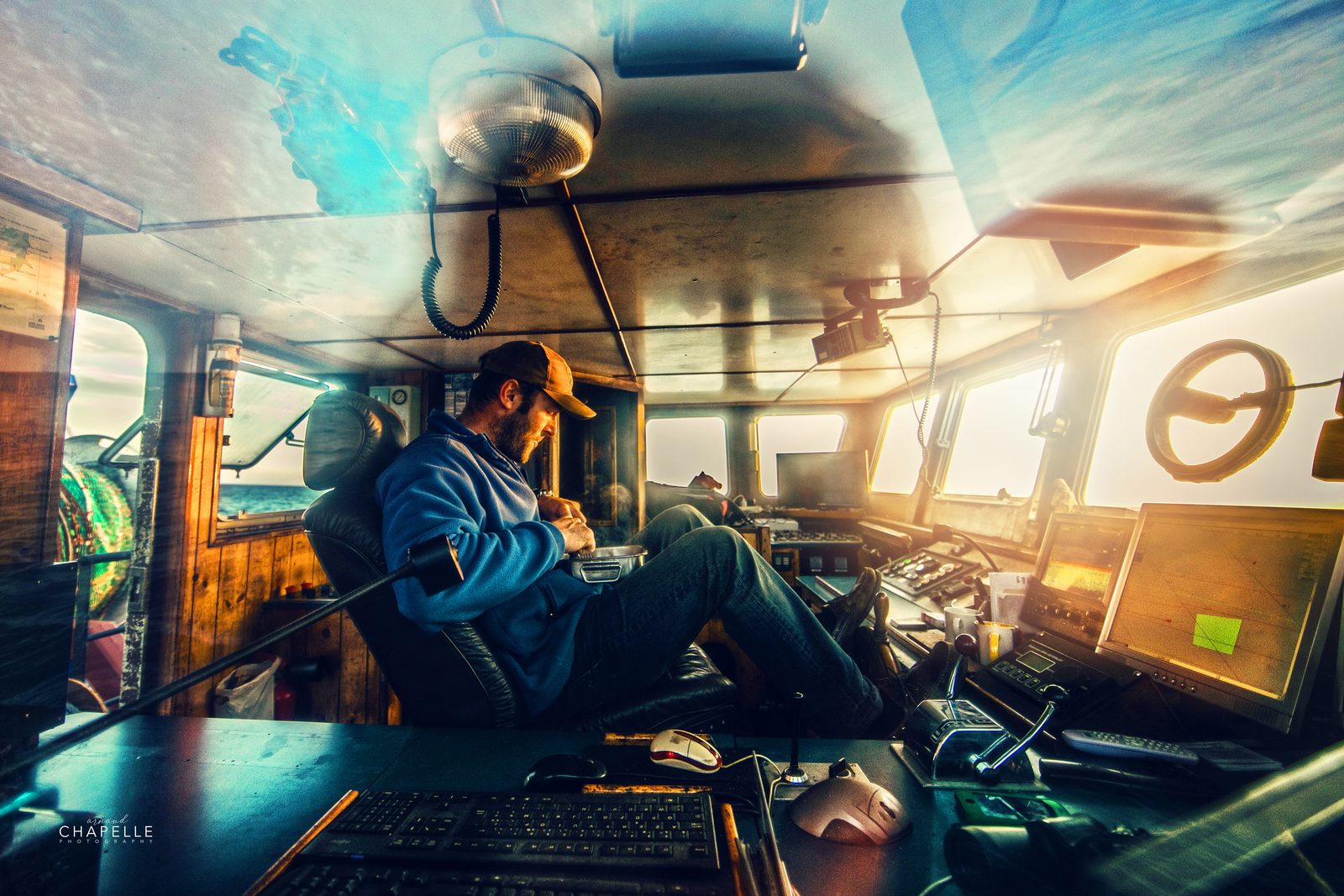 Un marin assis dans la cabine de pilotage du Télémaque, lumière du large par les vitres — Arnaud Chapelle
