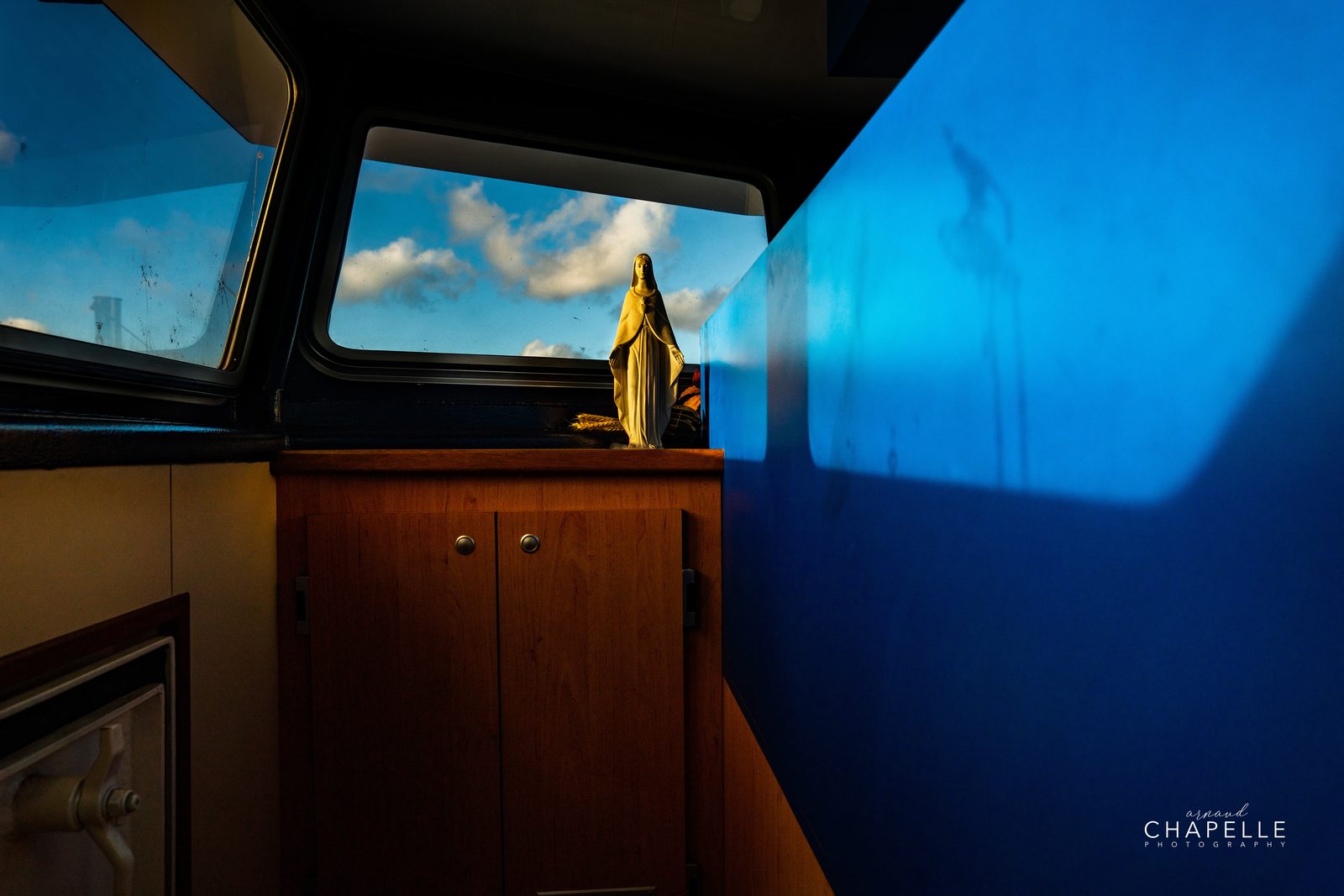 Une statuette de la Vierge dans la cabine du Télémaque, la mer par la fenêtre — Arnaud Chapelle