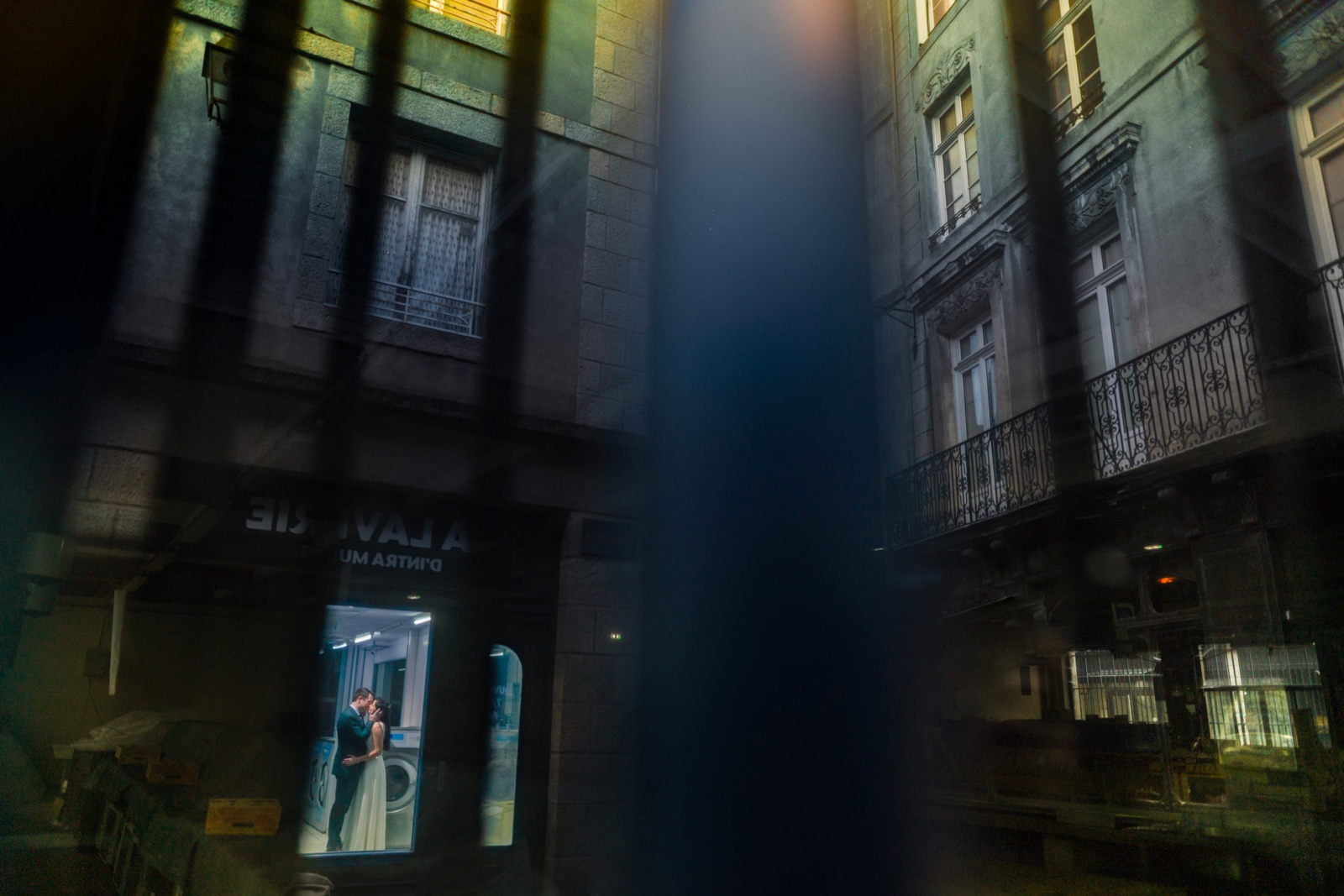 Marine et Alexandre dans l'encadrement d'une vitrine éclairée, la rue de granit dans l'obscurité — Saint-Malo la nuit — Arnaud Chapelle