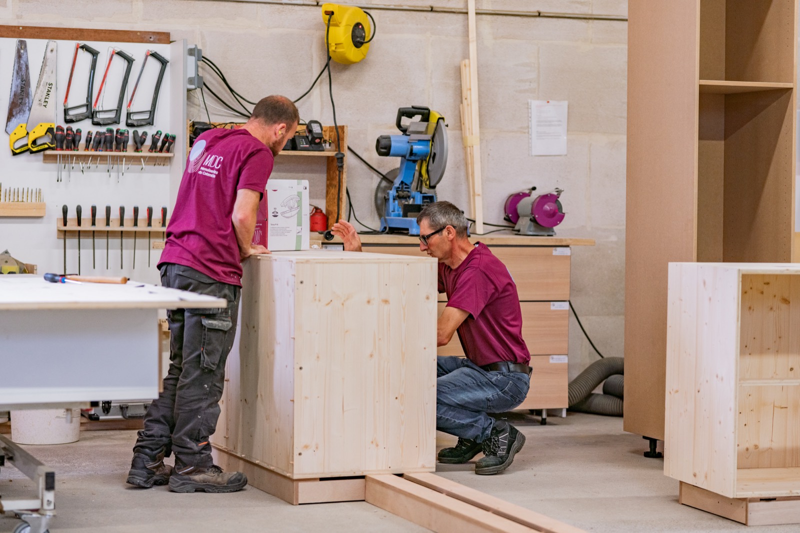 Assemblage d'un caisson en bois massif à deux, devant le panneau d'outils de l'atelier — Menuiseries du Cotentin — Arnaud Chapelle