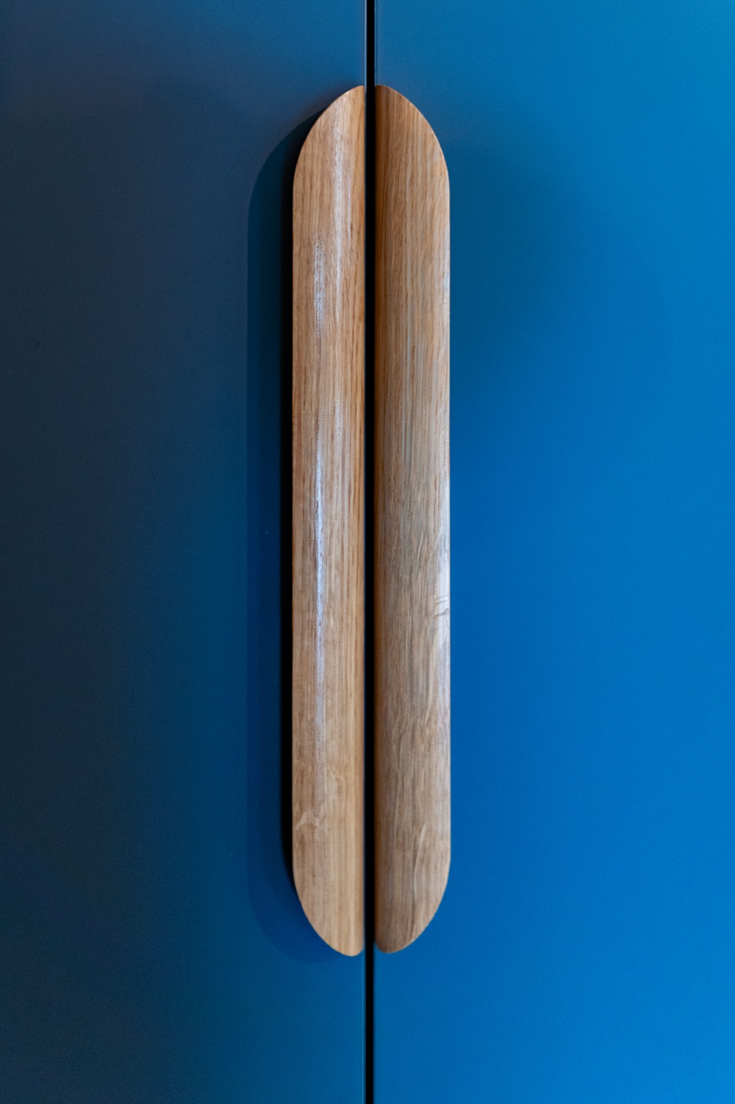 Poignée de bois massif sur une façade bleue, détail de fabrication sur mesure — Menuiseries du Cotentin — Arnaud Chapelle