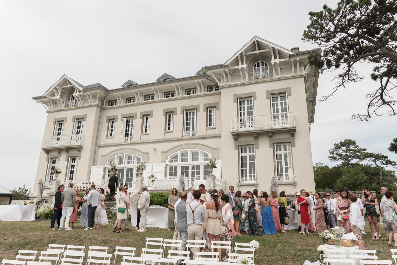 Les invités devant la façade du Château de la Crête et les chaises blanches alignées pour la cérémonie — mariage à Granville (Manche) — Arnaud Chapelle