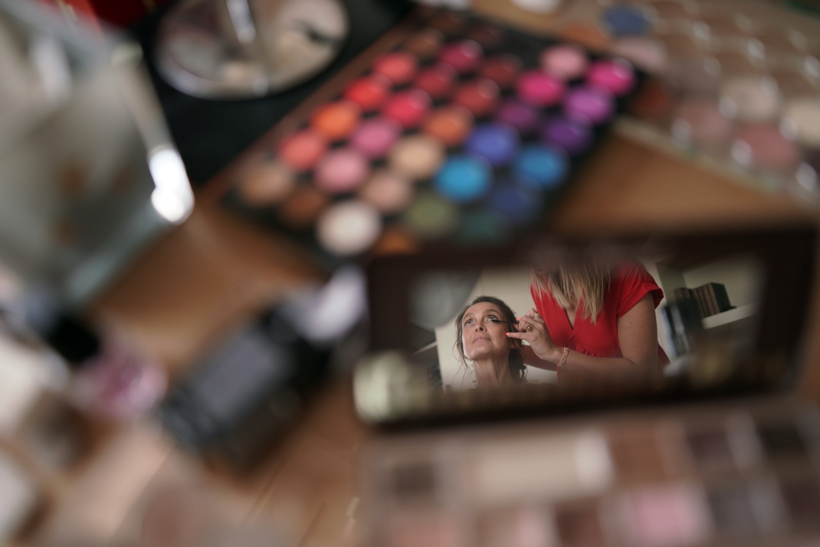 Le maquillage de la mariée reflété dans un petit miroir posé au milieu des palettes de fards — préparatifs, mariage au Château de la Crête, Granville — Arnaud Chapelle