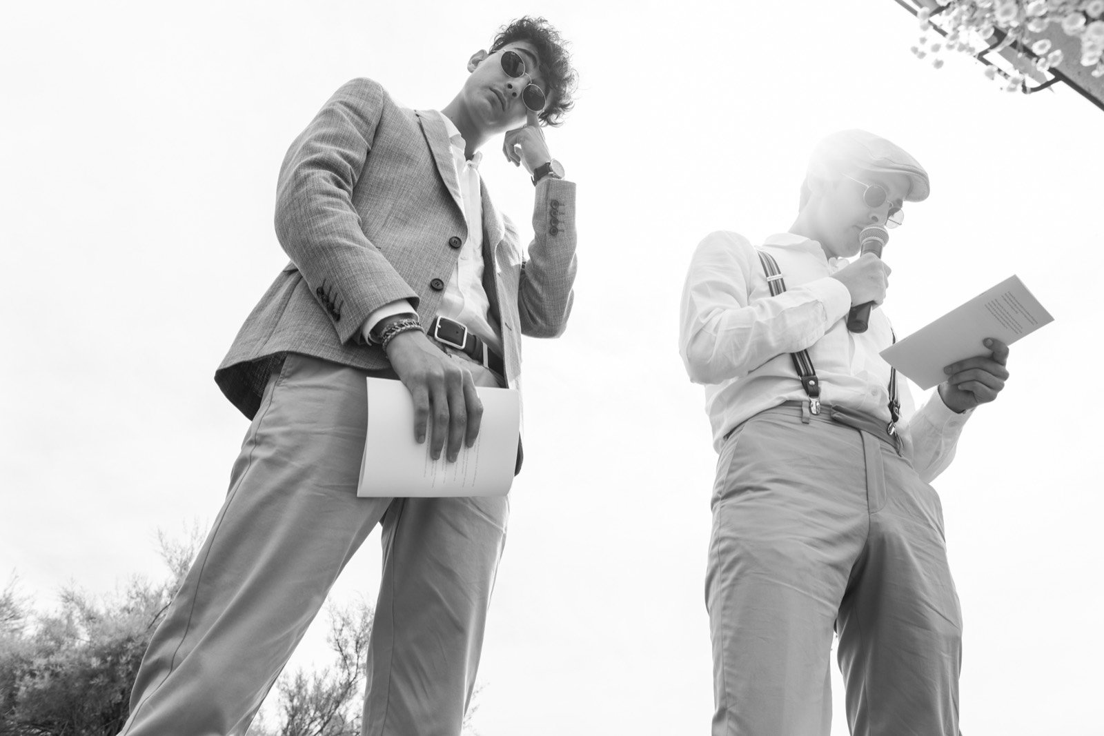 Deux témoins lisent leur discours au micro, photographiés en contre-plongée en noir et blanc — cérémonie de mariage au Château de la Crête, Granville — Arnaud Chapelle