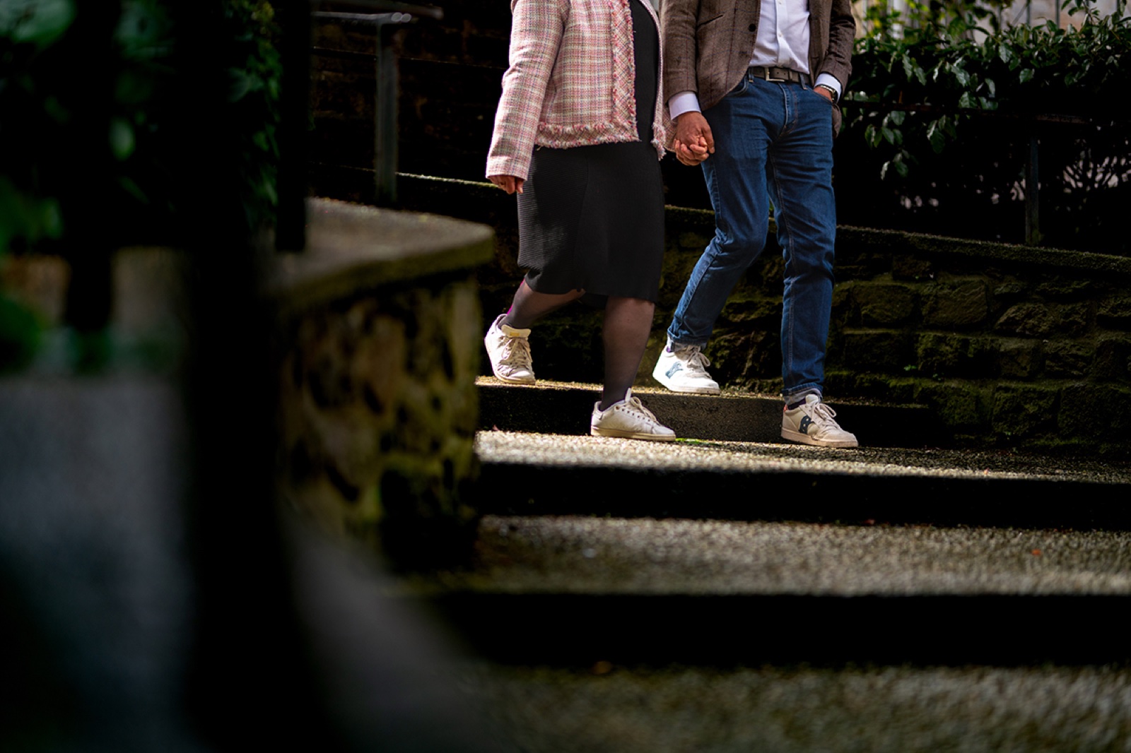 Détail des mains du couple qui descend un escalier de pierre — séance engagement à Saint-Malo — Arnaud Chapelle
