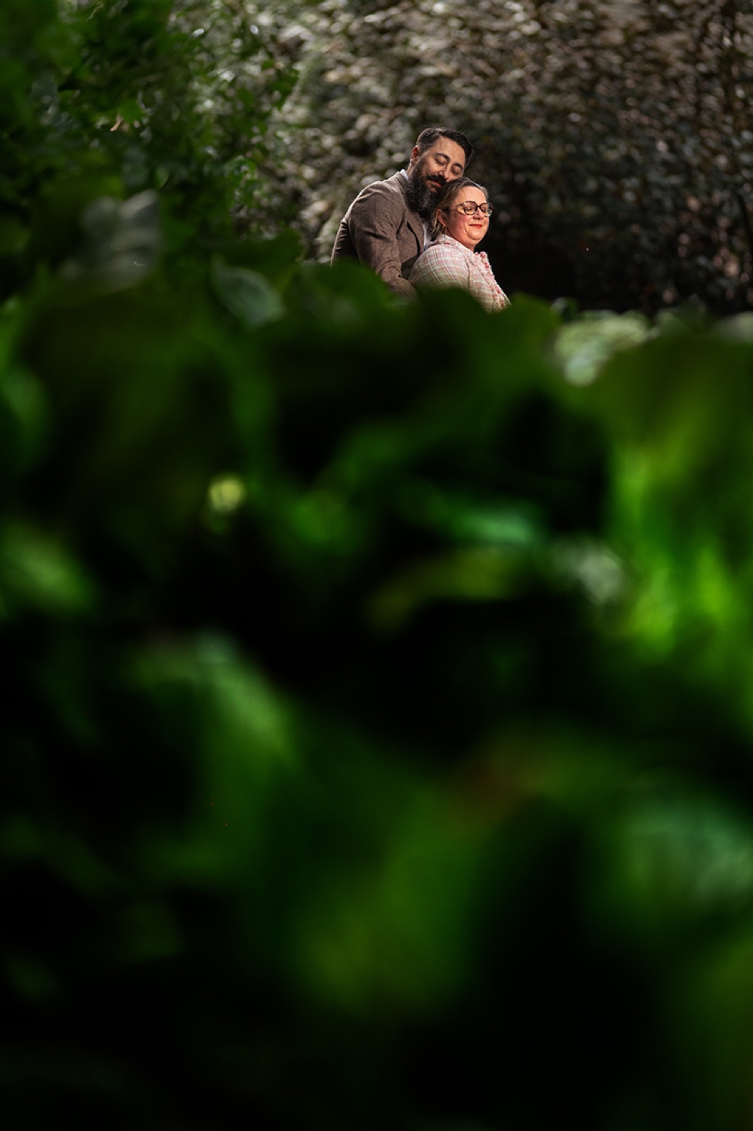 Le couple enlacé, aperçu à travers le feuillage — séance engagement à Saint-Malo — Arnaud Chapelle