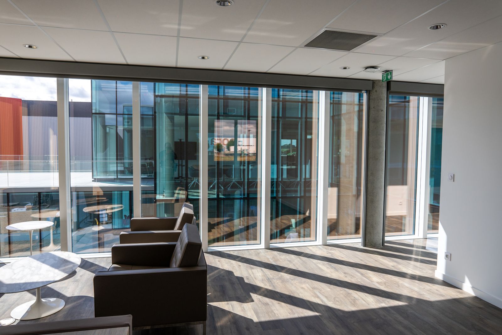 Glass-walled office lobby, armchairs in the light