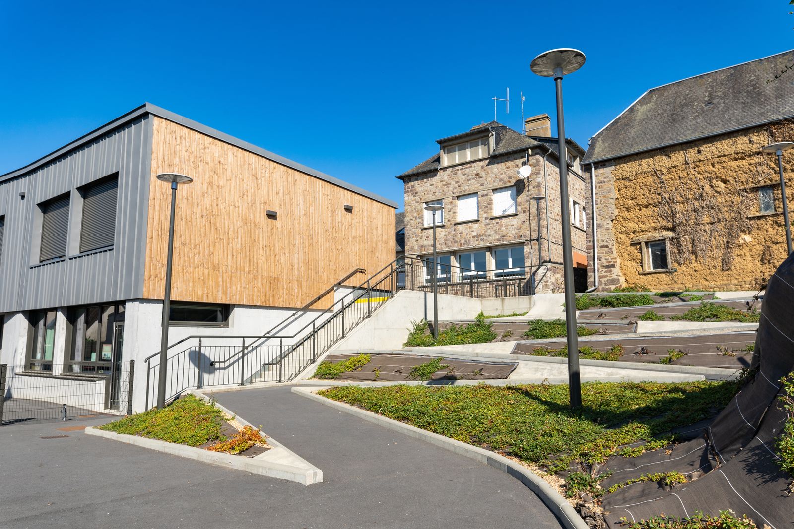 Timber and metal-clad extension beside stone houses