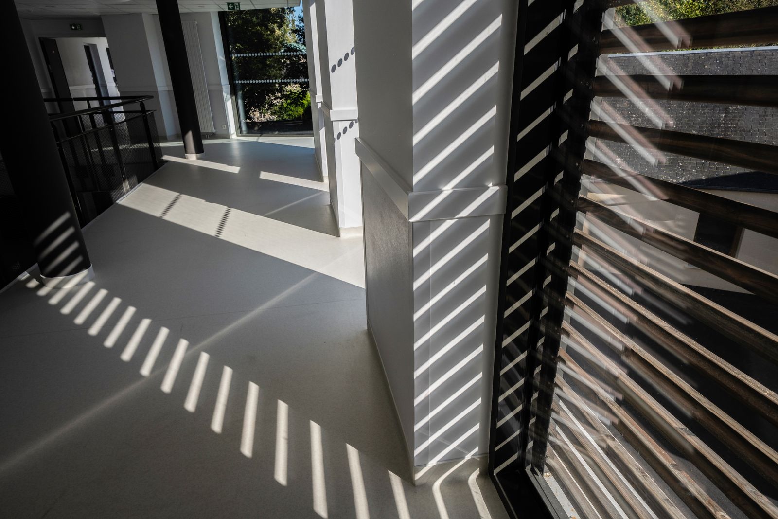 Shadows of sun louvres across a school corridor