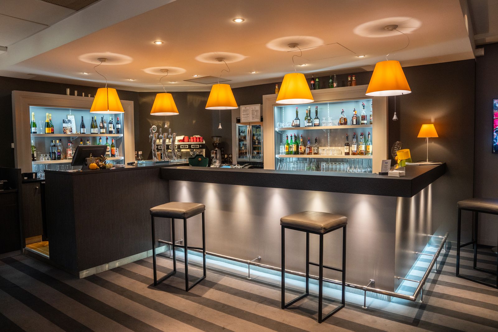 Hotel bar, orange lampshades and lit shelves