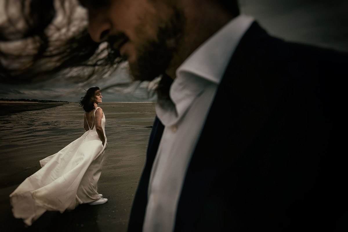 Bride and groom on a Normandy beach under a stormy sky, wedding photographer Arnaud Chapelle