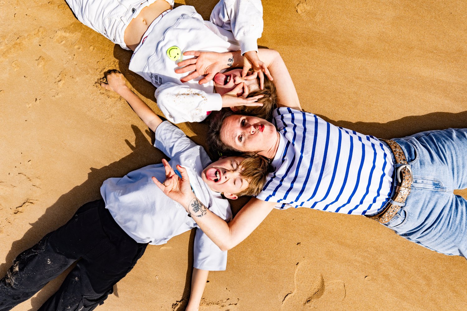 Overhead photograph of a mother and her two children lying on the sand of Omaha Beach