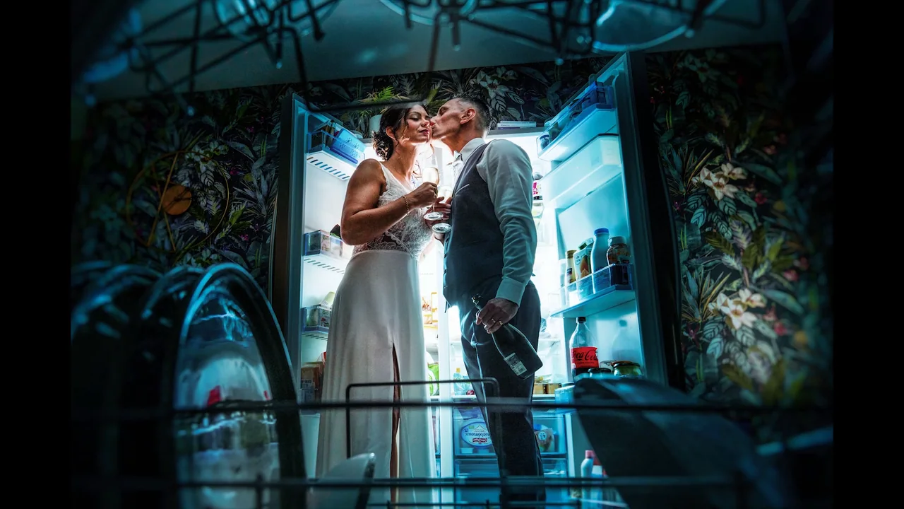 A married couple kiss, a glass in hand — wedding reportage in Normandy by Arnaud Chapelle