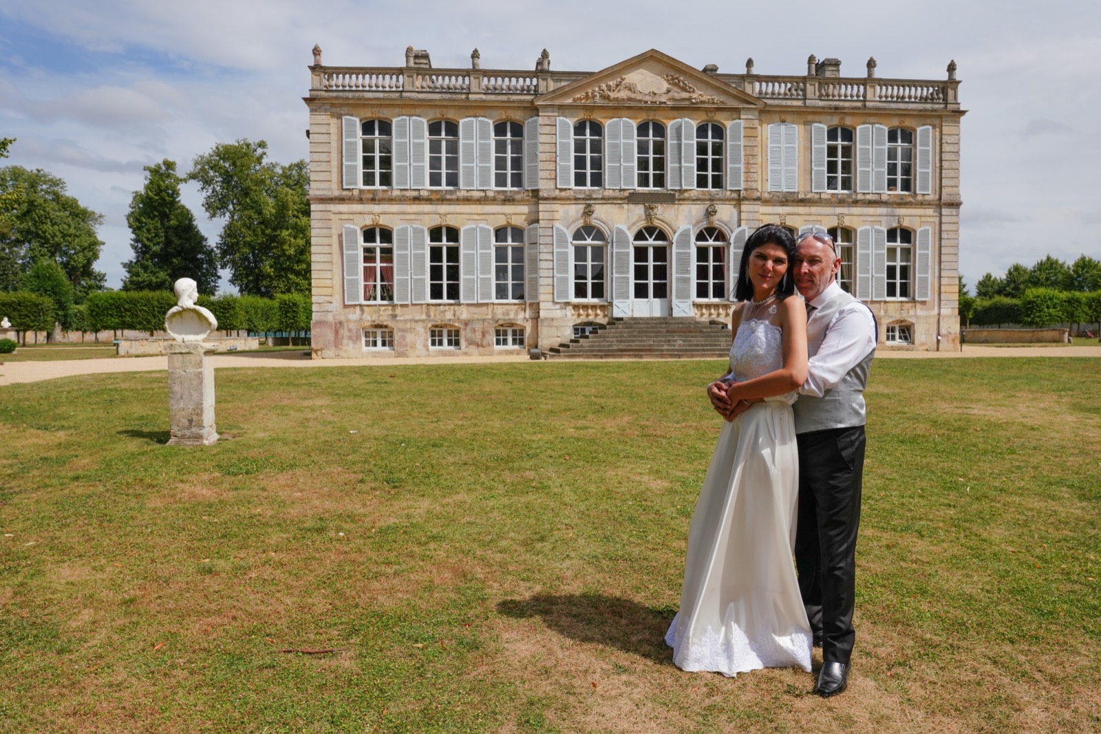 Les mariés devant la façade du Château de Canon, au soleil — lieu de mariage à Mézidon, dans le Pays d'Auge (Calvados) — Arnaud Chapelle