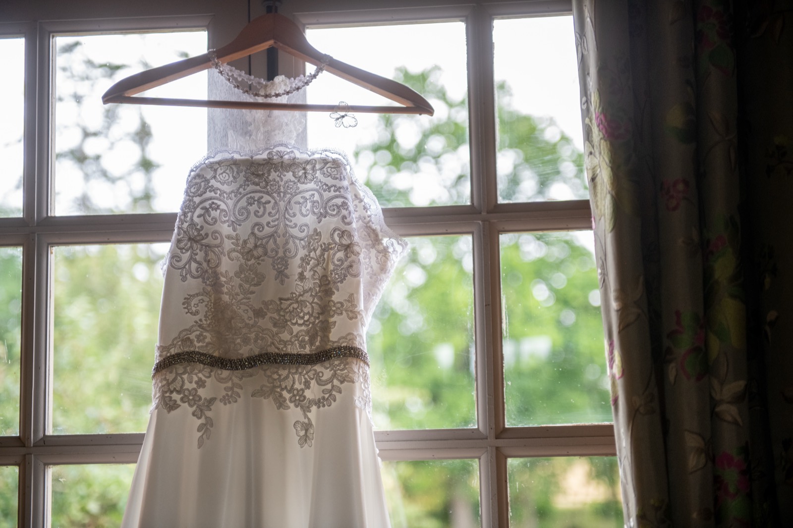 La robe de mariée en dentelle suspendue à une fenêtre — préparatifs d'un mariage au Château de Canon (Calvados) — Arnaud Chapelle