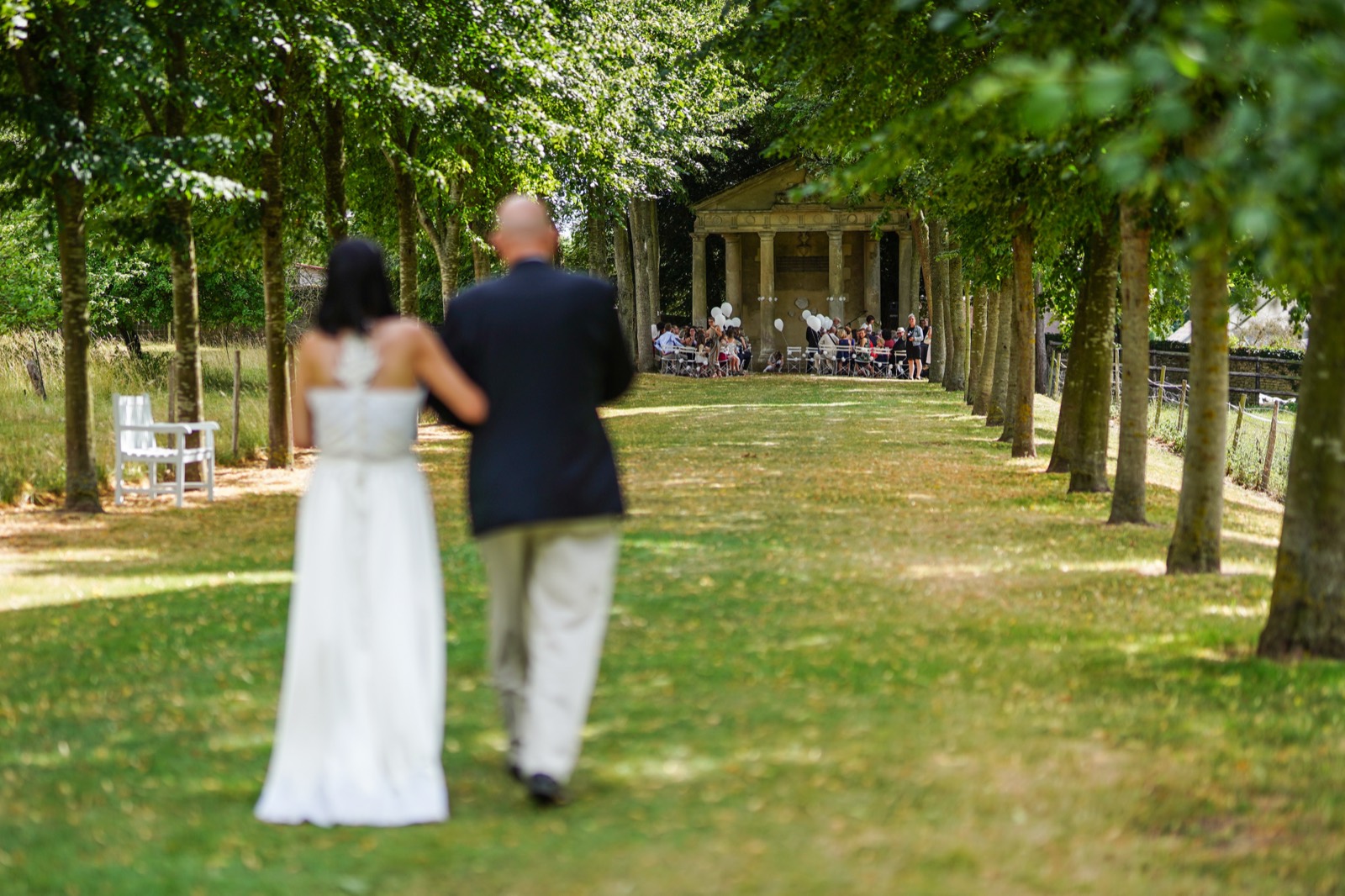 Les mariés remontent une allée d'arbres vers la cérémonie, dans les jardins du Château de Canon — Mézidon, Pays d'Auge — Arnaud Chapelle