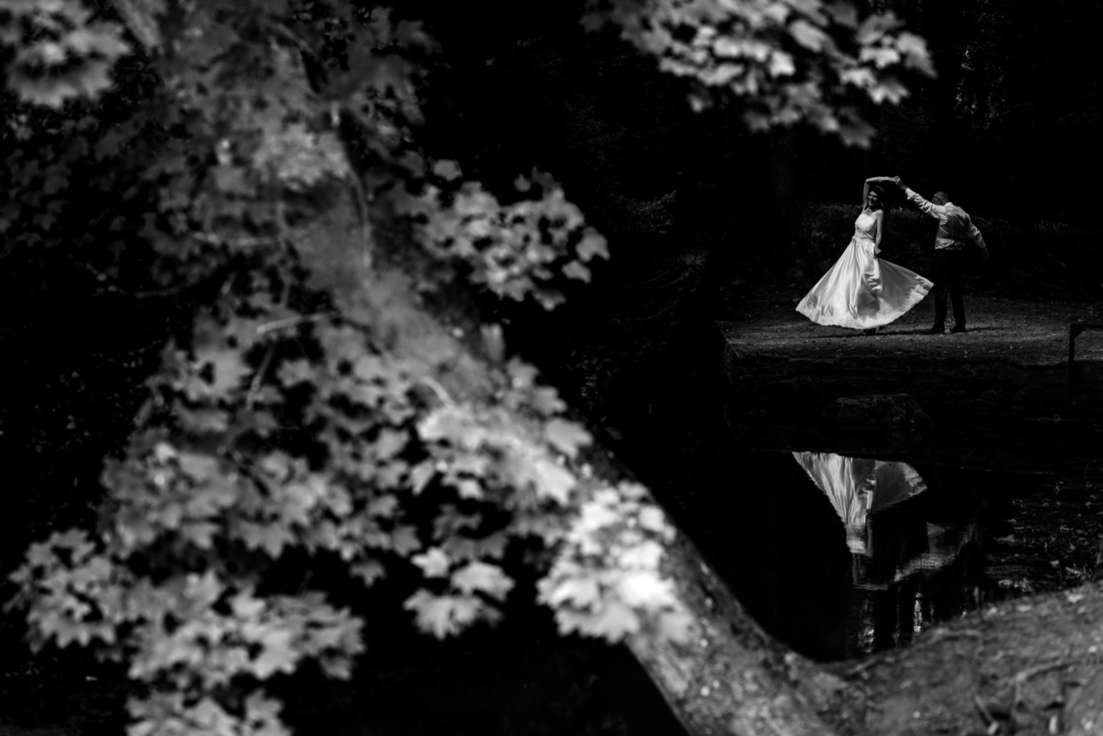 Les mariés au bord de l'eau, reflet dans le miroir d'eau, en noir et blanc — jardins du Château de Canon (Calvados) — Arnaud Chapelle