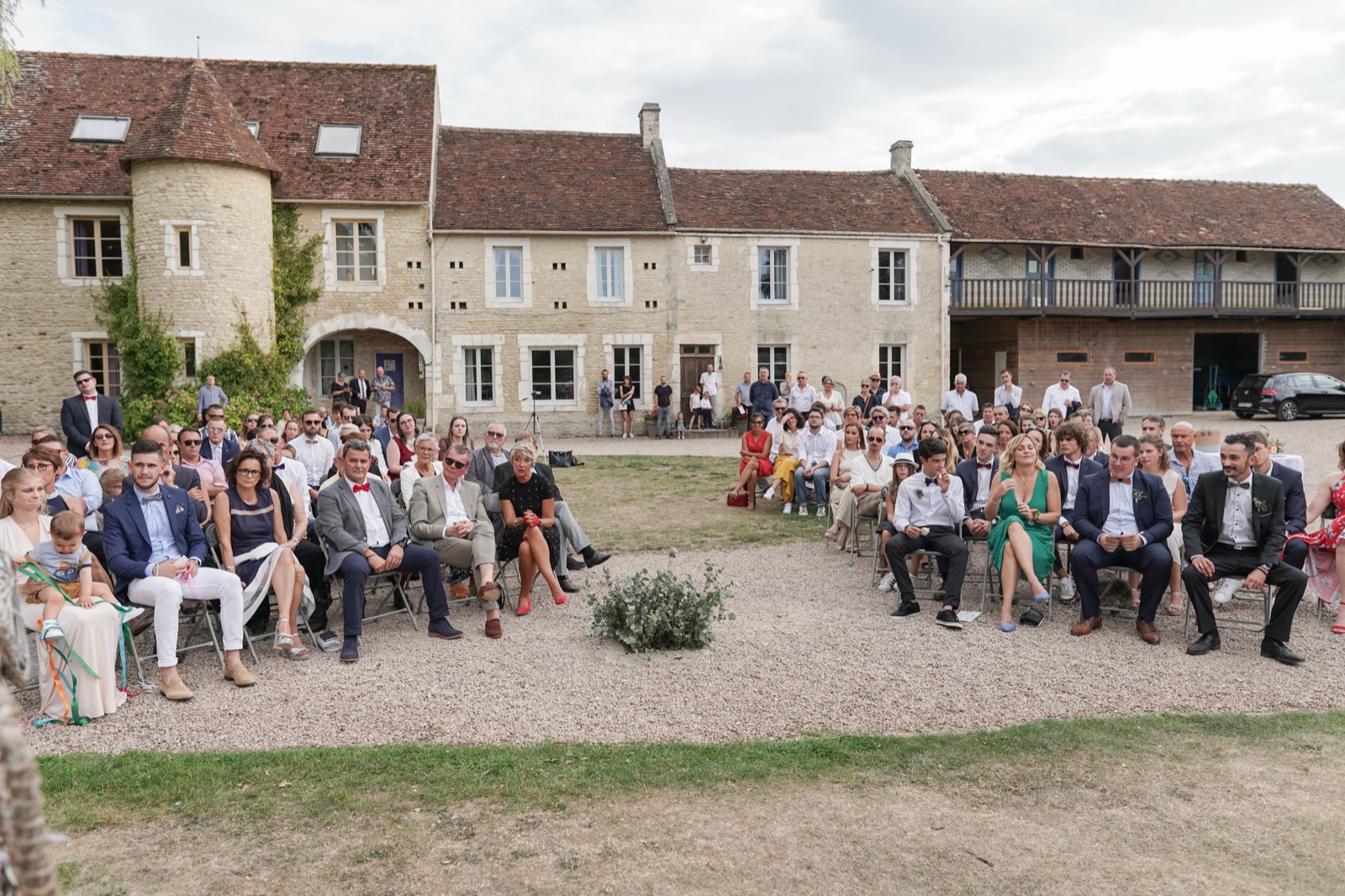 La cérémonie dans la cour de pierre du Cœur de Combray, devant le manoir et ses dépendances — lieu de mariage à Ernes, près de Caen (Calvados) — Arnaud Chapelle