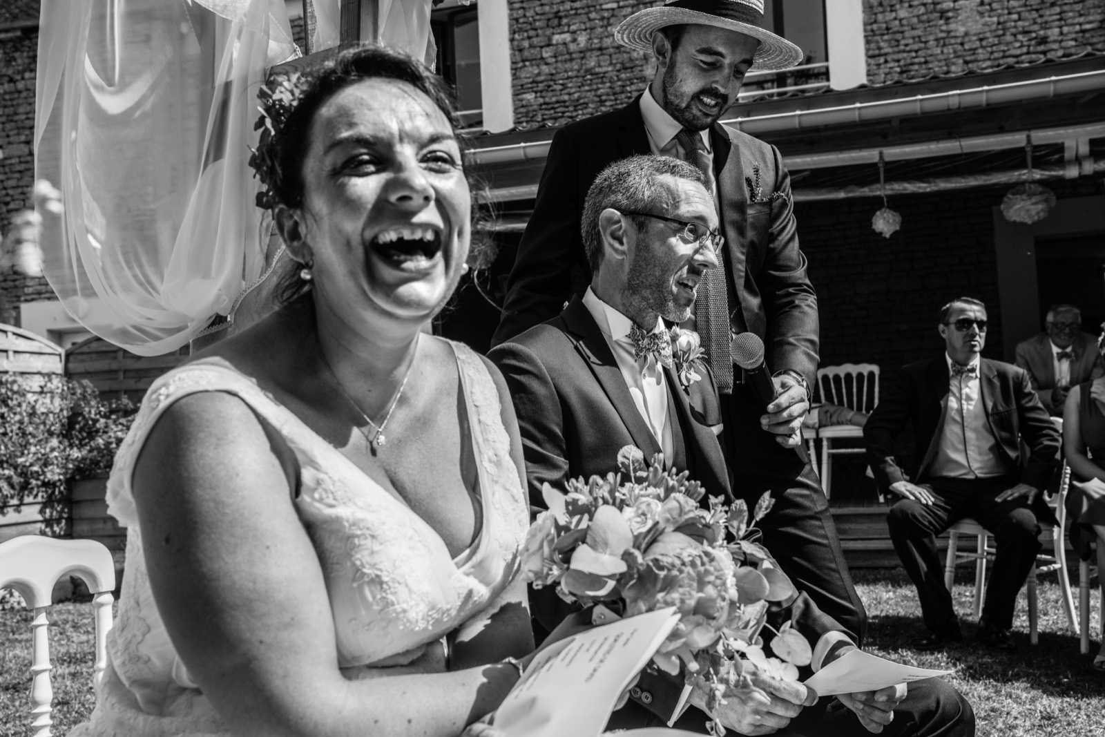 Fou rire de la mariée pendant la cérémonie laïque, en noir et blanc — mariage au Domaine de Cauvicourt (Calvados) — Arnaud Chapelle