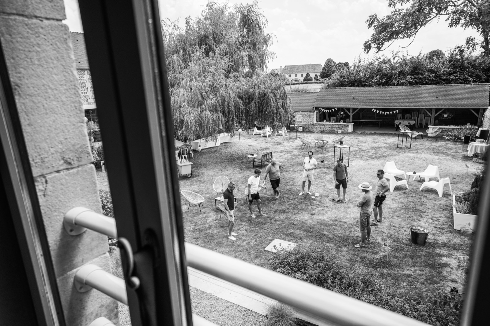 Jeux de jardin entre invités devant l'abri du domaine, en noir et blanc — mariage au Domaine de Cauvicourt, entre Caen et Falaise — Arnaud Chapelle