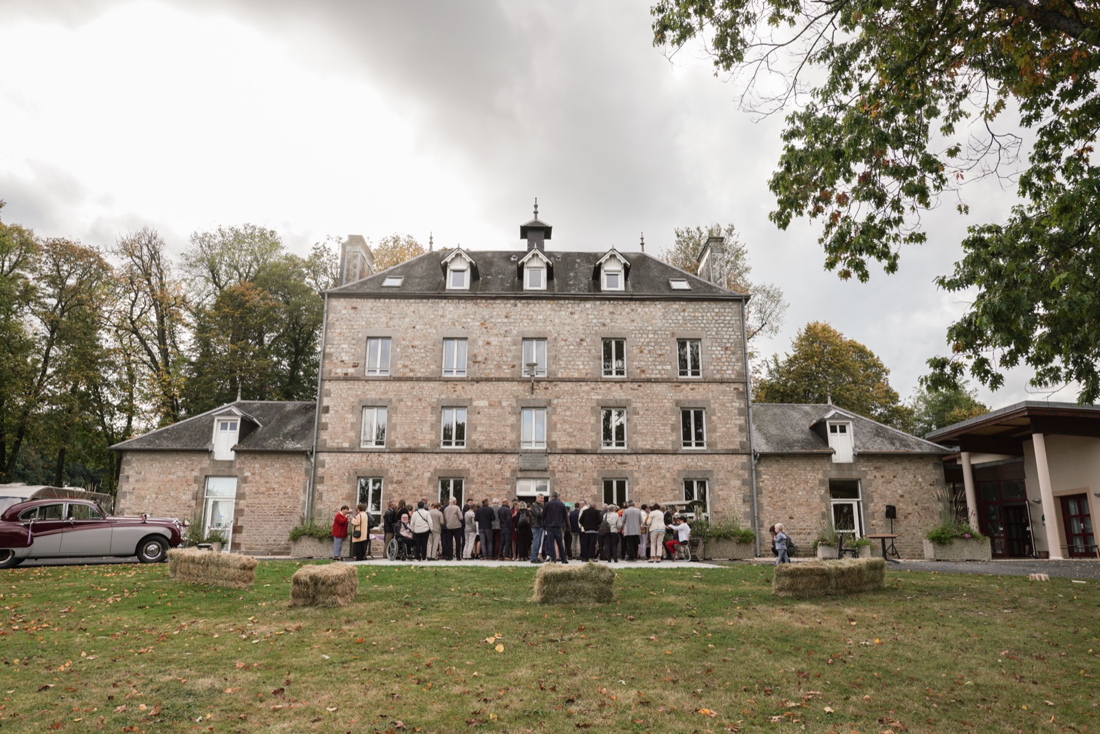 Le manoir de pierre du Domaine de Pont-Ramond, les invités et une voiture ancienne devant la façade — lieu de mariage à La Chapelle-au-Moine, près de Flers (Orne) — Arnaud Chapelle