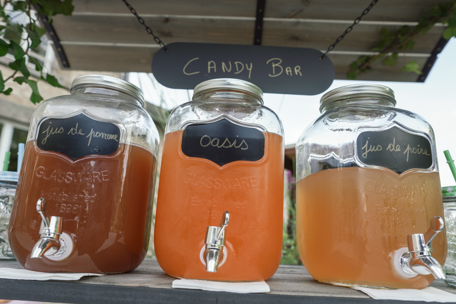 Le « candy bar » et ses bonbonnes de jus de pomme et de poire — détail d'un mariage au Domaine de Pont-Ramond (Orne) — Arnaud Chapelle