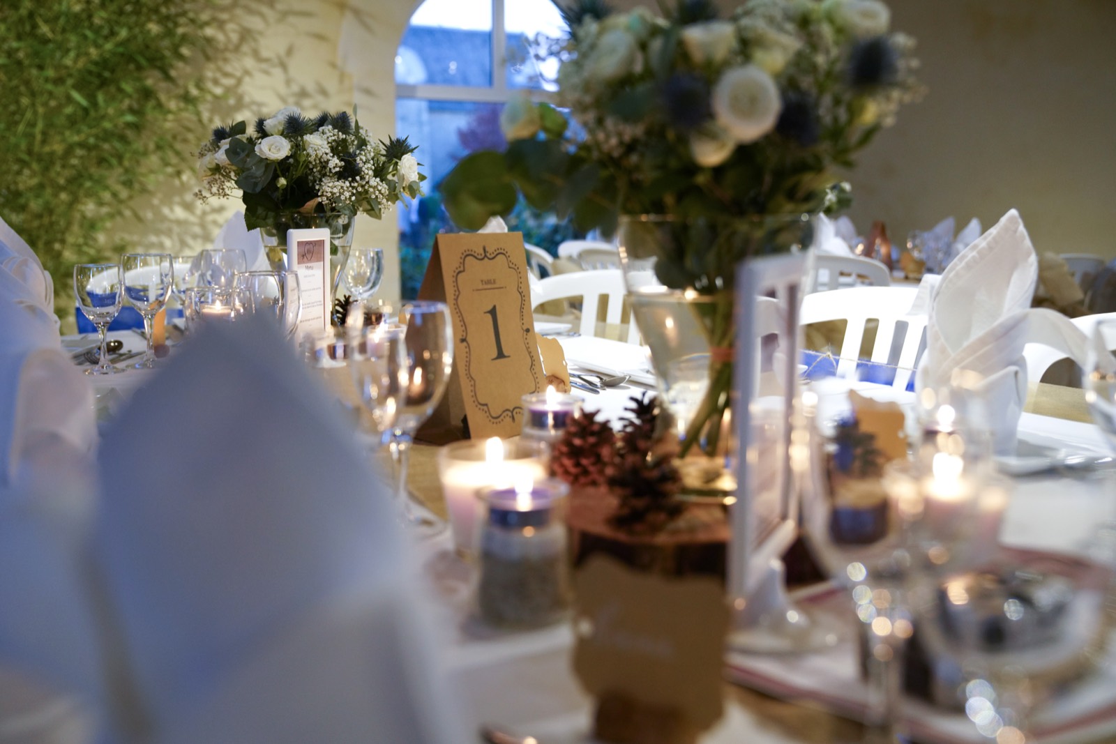 Détail de table — bouquet de chardons et gypsophile, bougies et pommes de pin — mariage au Domaine du Grand Caugy — Arnaud Chapelle