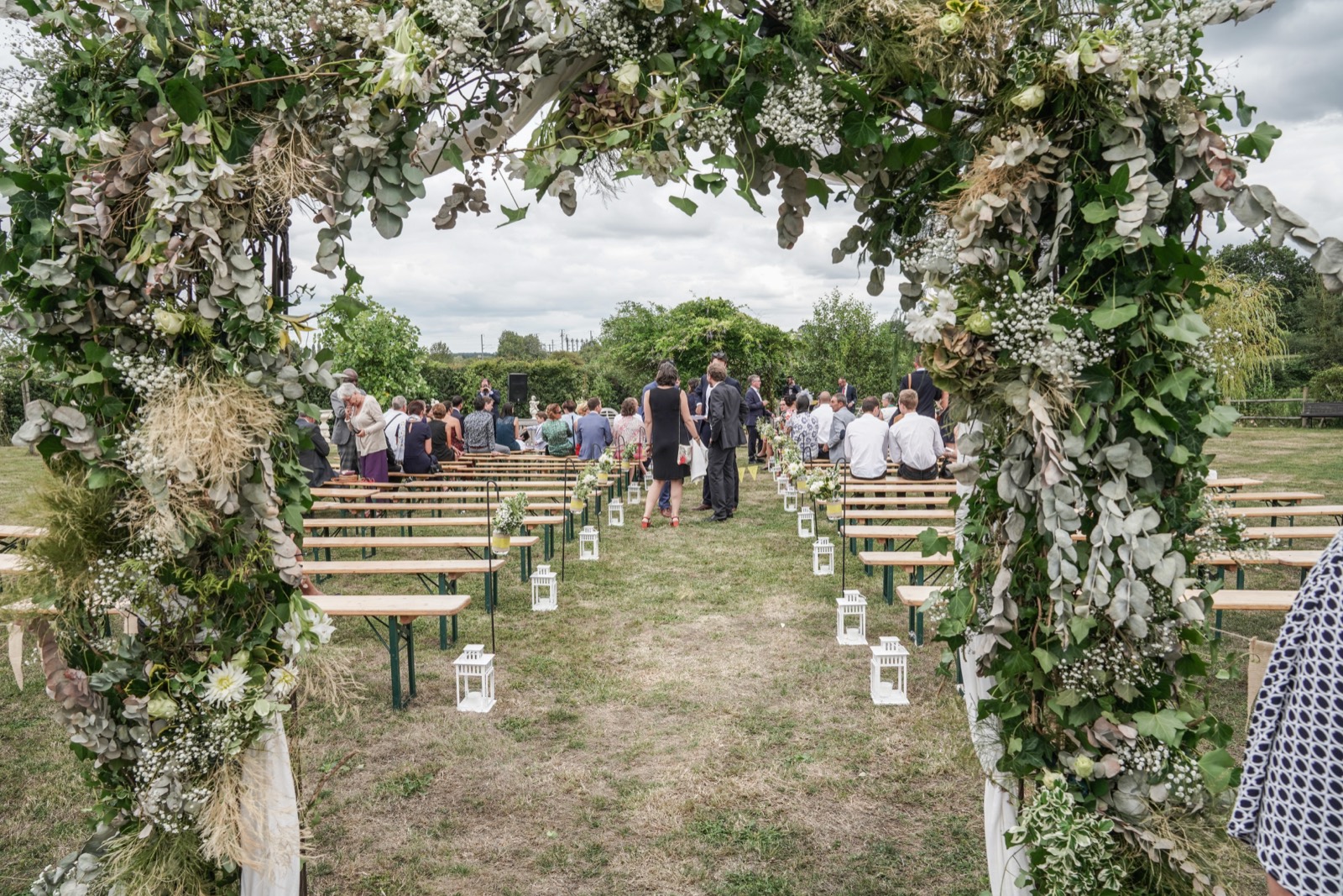 L'allée de la cérémonie sous une arche d'eucalyptus et de gypsophile — mariage au Manoir de Chivré (Calvados) — Arnaud Chapelle