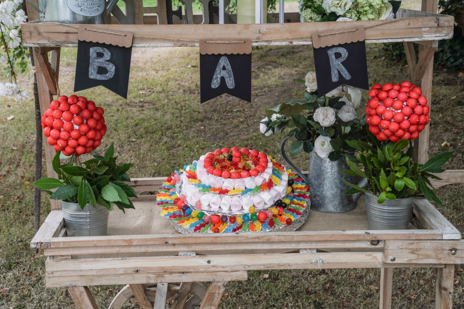 Le « bar à bonbons » et le gâteau coloré dans le parc — détail d'un mariage au Manoir de Chivré (Calvados) — Arnaud Chapelle