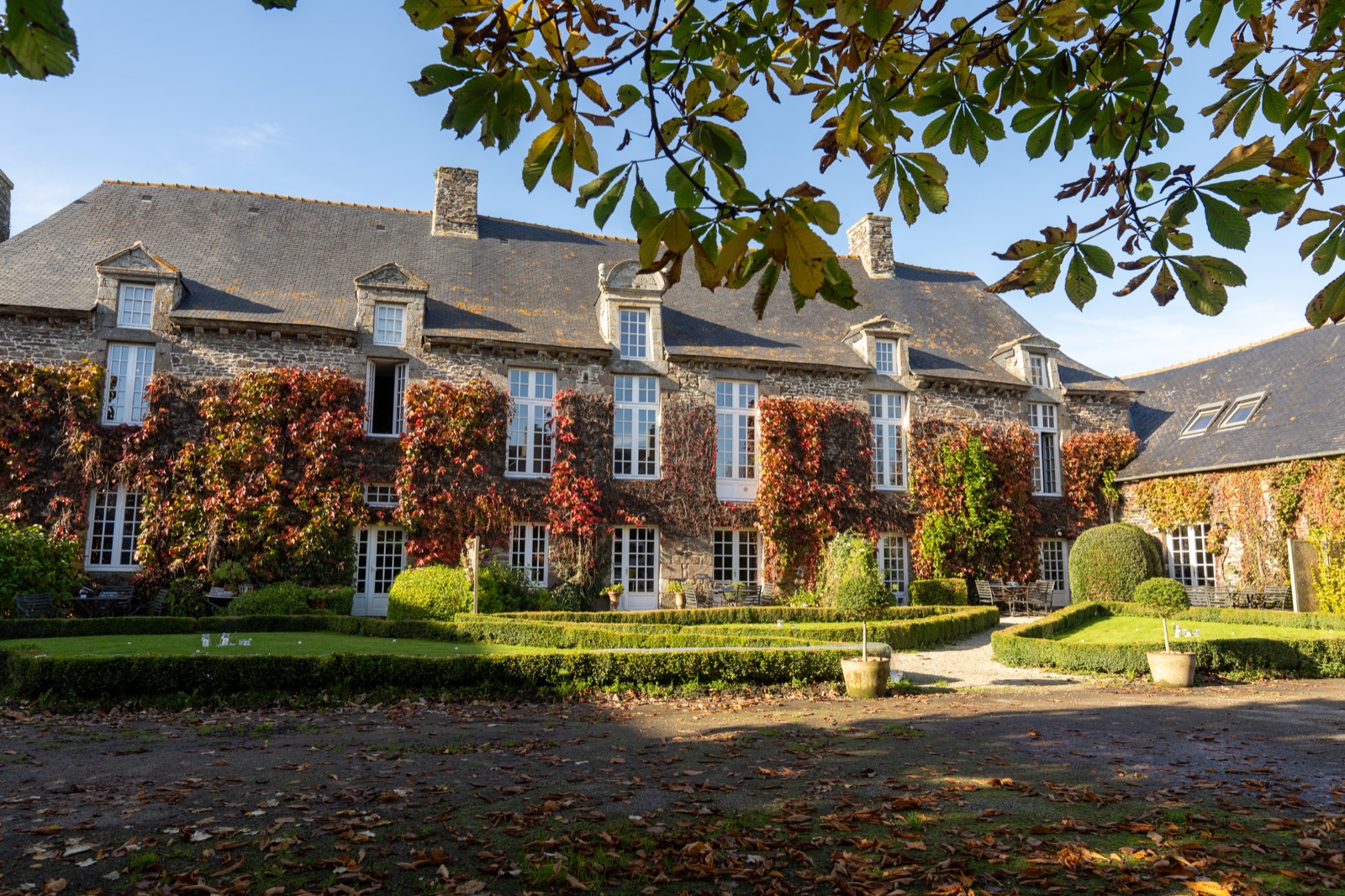 Le Manoir de la Bégaudière à Mont-Dol — façade de pierre couverte de vigne vierge et jardin à la française, en automne — lieu de mariage en baie du Mont-Saint-Michel — Arnaud Chapelle