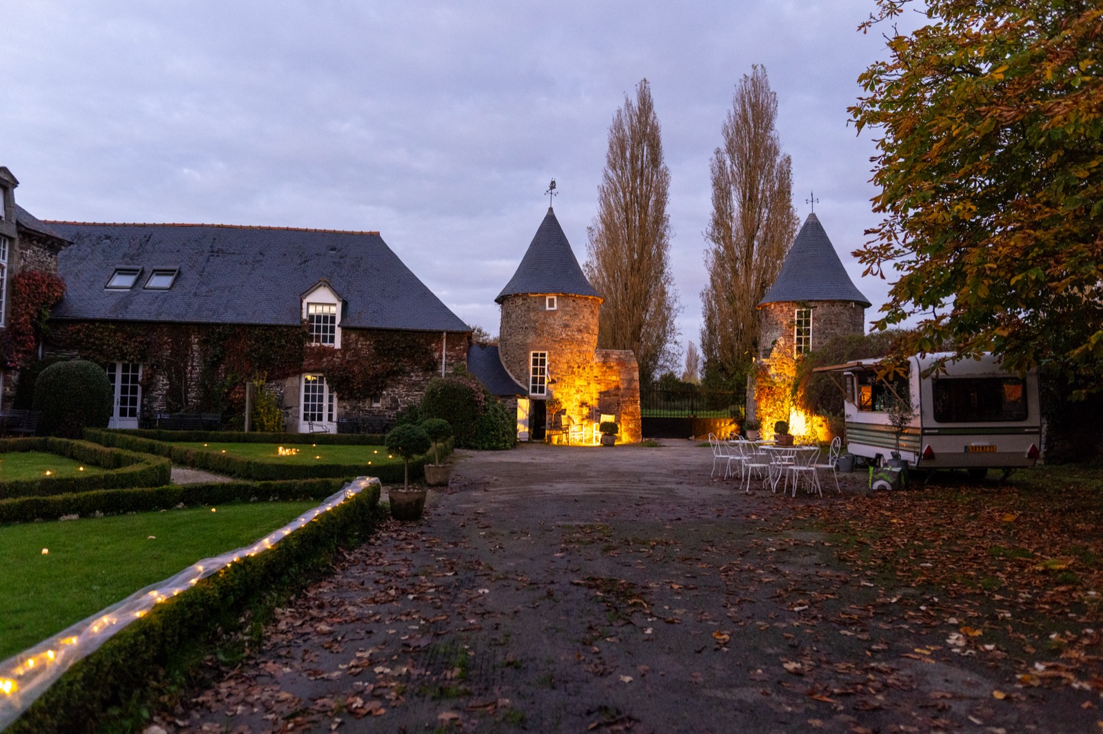 Le manoir et ses tourelles illuminés à la tombée de la nuit, allée bordée de guirlandes — Manoir de la Bégaudière, Mont-Dol — Arnaud Chapelle
