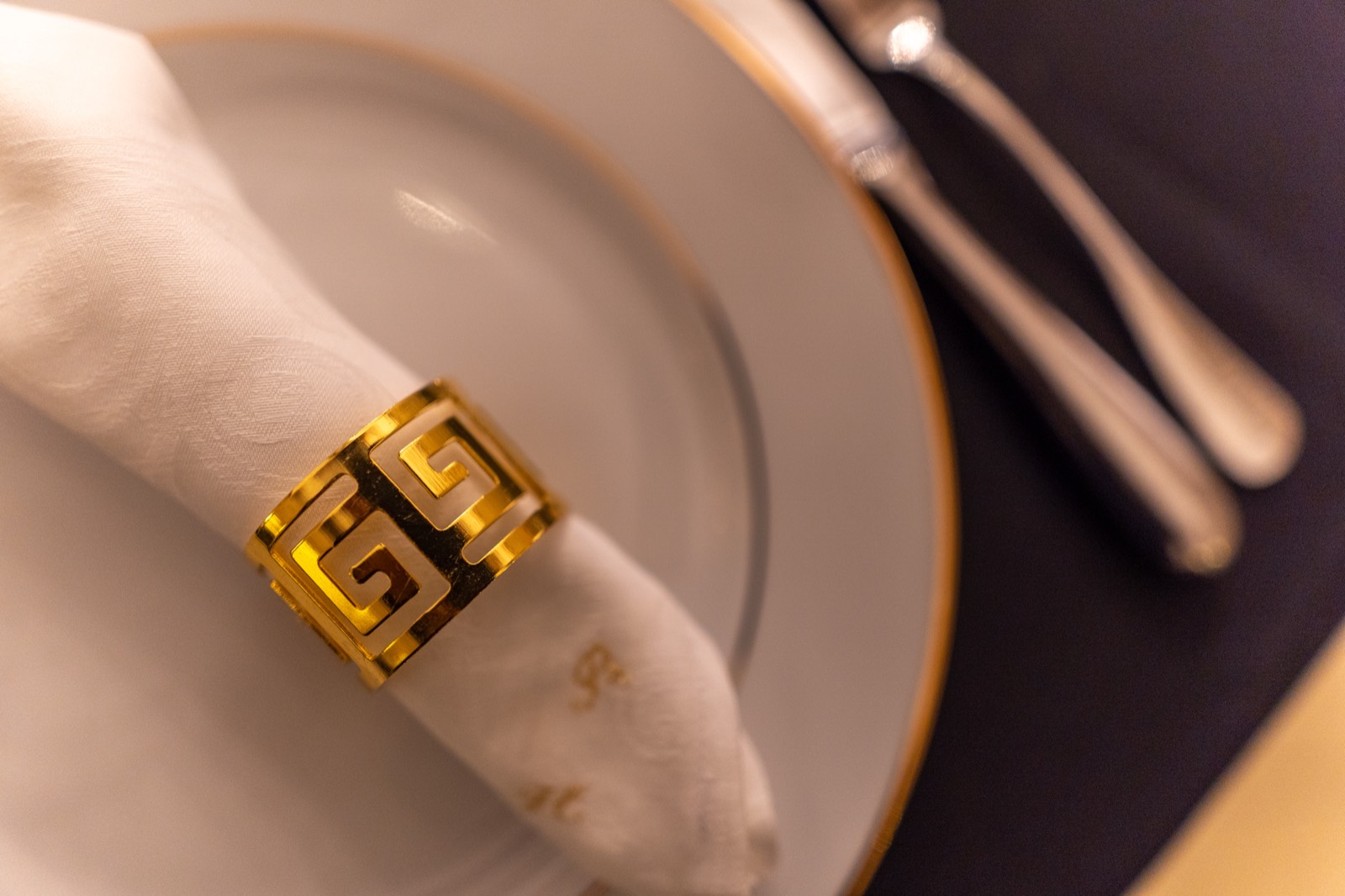 Détail de table — assiette, rond de serviette doré — dîner de mariage au Manoir de la Bégaudière, Mont-Dol — Arnaud Chapelle