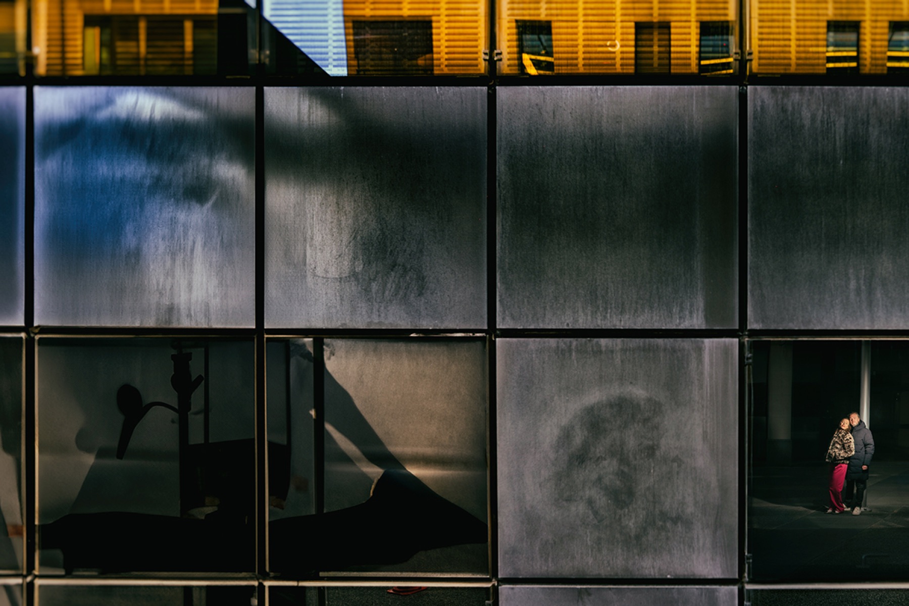 Séance photo de couple en ville — couple dans une façade de verre, style cinématique — Urban Love par Arnaud Chapelle